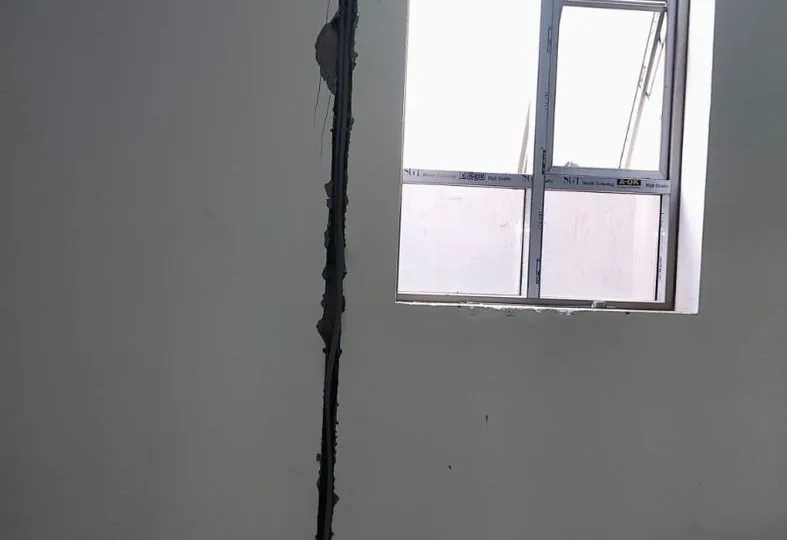 التمديدات الكهربائية قبل اللياسة: المجاري والعلب وما يراجع قبل إغلاق الجدار مجرى رأسي لماسورة كهرباء من الأرضية حتى السقف بجانب نافذة في منزل بحي القيروان