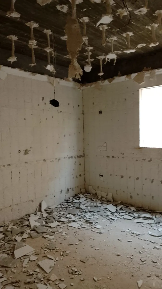 غرفة بعد إزالة السقف الجبسي وبلاط الجدران في مرحلة التكسير بمشروع ترميم فيلا في الرياض